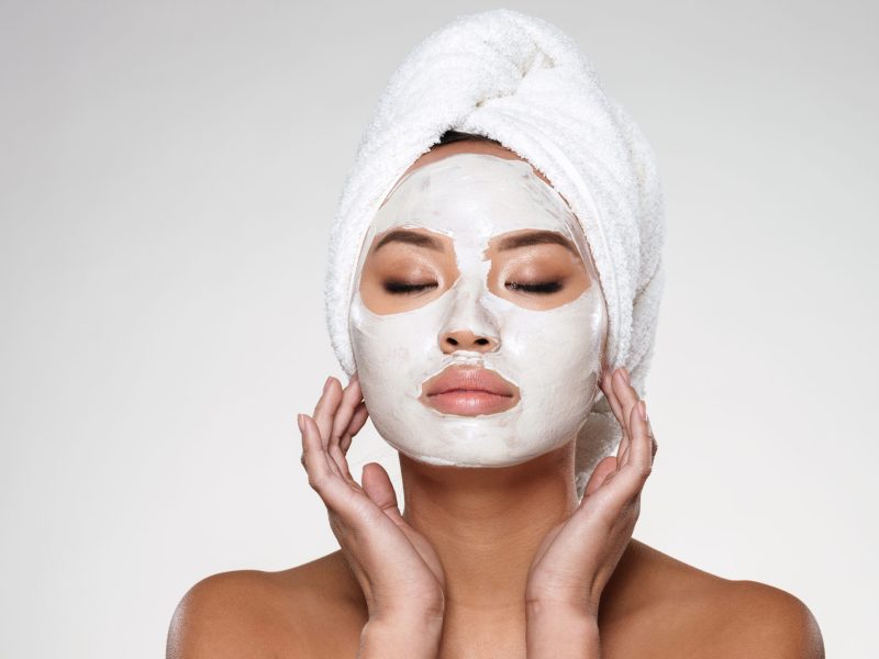 Portrait of beautiful lady with closed eyes and towel on her head put scrab on her face isolated